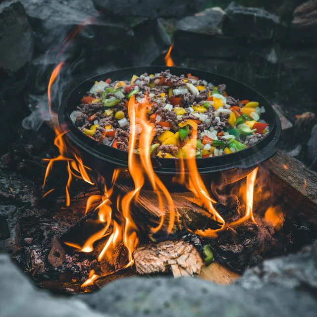in einem Feuertopf Deckel wird auf offenem Feuer ein Pfannengericht gebraten