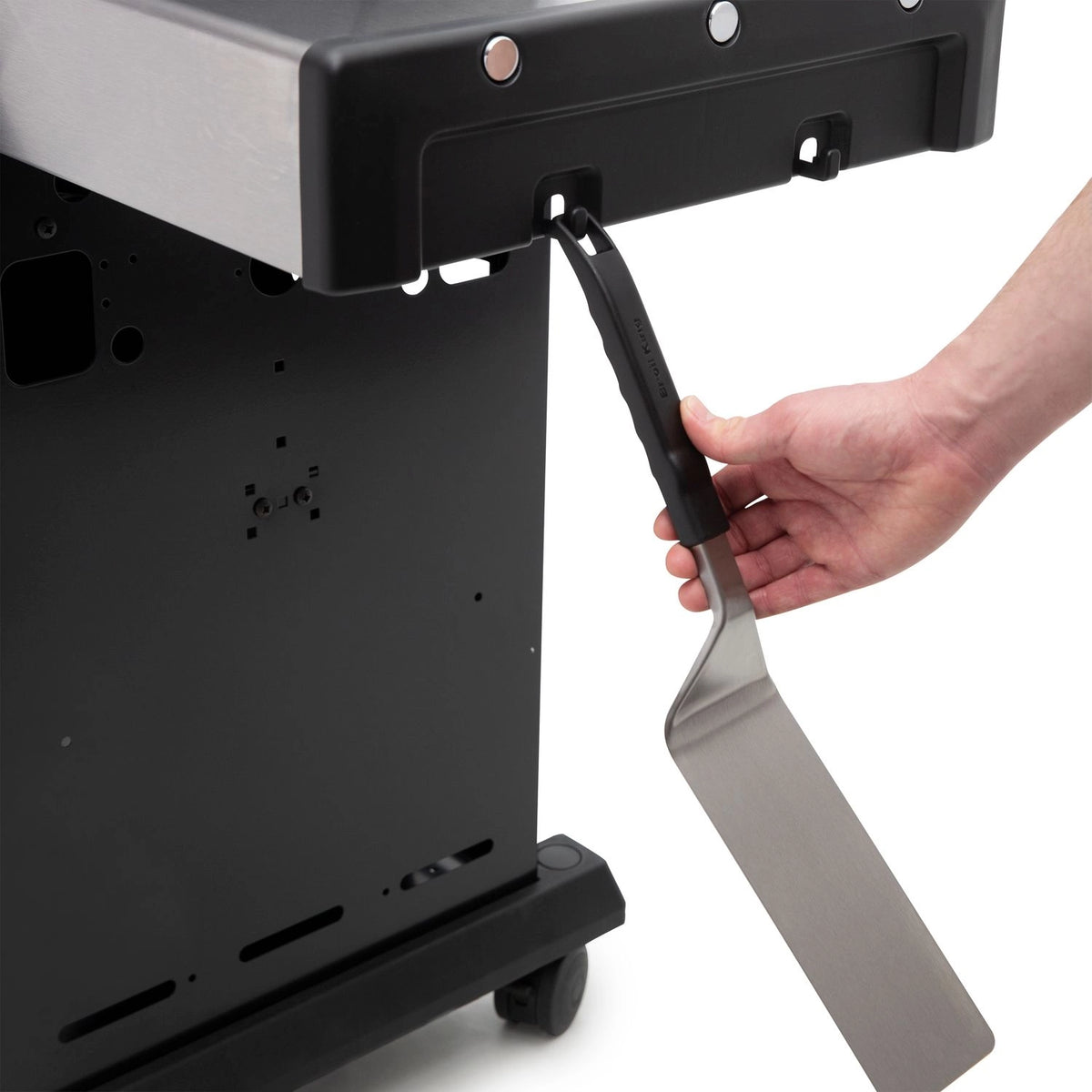 ein Grillwender wird an die Haken an der Seitenablage beim Baron 490 Grill gehängt