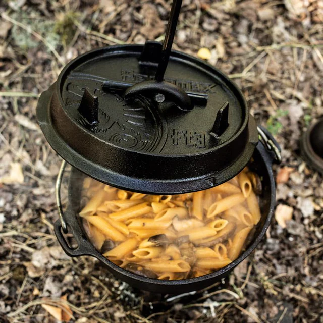 gekochte Nudeln in einem Feuertopf bei dem ein Deckelheber den Dutch Oven Deckel anhebt